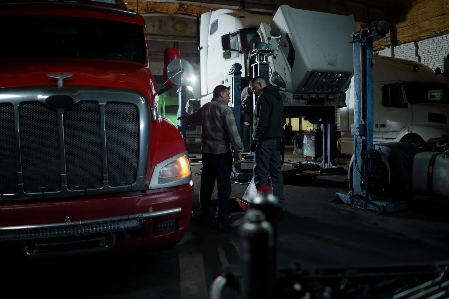 Technician performing work on a truck in an indoor garage setting.