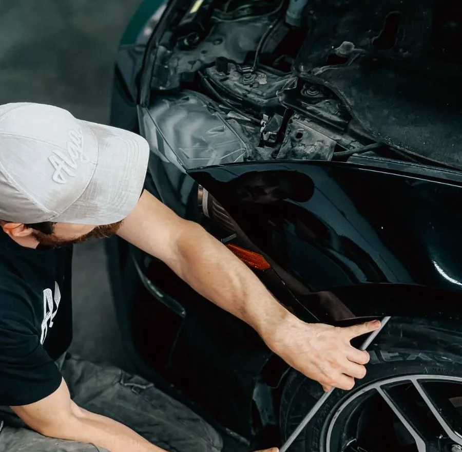 Technician working meticulously on a car bumper repair inside an auto garage.