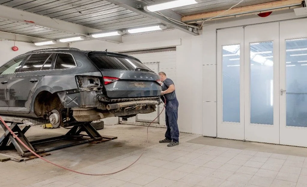 Technician repairing a car indoors at an auto workshop, working on the vehicle.
